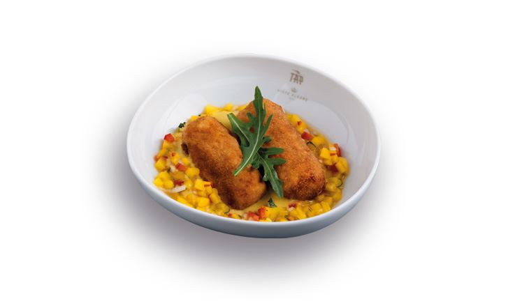 Zdjęcie białego talerza z logo TAP, z dwoma krokietami z morszczuka w sosie curry i mango.