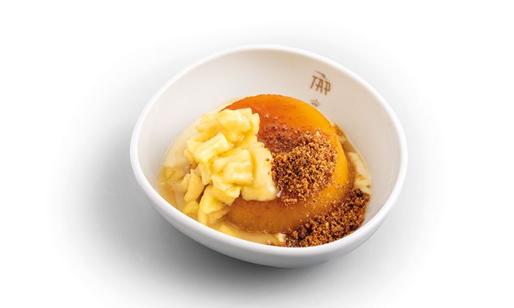 Fotografia de um prato branco com o logótipo da TAP, com uma sobremesa de Pudim de Maçãs das Beiras, Creme de Canela e Amêndoa.