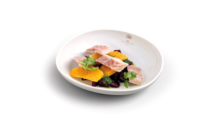 Photograph of a white plate, with the golden TAP logo on the edge. On the plate is river fish, beetroot and orange salad.